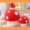 Three plush mushroom toys of different sizes are arranged on a sofa. The largest mushroom is in the center, with a smaller one stacked on top, and another one to the right. The background shows a blurred interior scene with a lamp and shelves. Produktbild-Vorschau