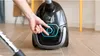 A person's hand is adjusting the settings on a black vacuum cleaner. Produktbild-Vorschau