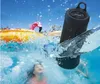A black Hama Bluetooth speaker is submerged in a swimming pool with water splashing around it. Children are visible swimming in the background, along with inflatable pool toys. Náhled obrázku produktu