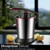 A close-up of a citrus juicer with lemons in the foreground, set against a blurred background of greenery and a window view. Produktbild-Vorschau