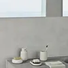 A bathroom countertop with various accessories, including a soap dish, soap dispenser, toothbrush holder, and a towel. Produktbild-Vorschau