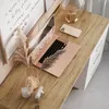 A desk setup with a laptop, phone, camera, candle, and dried flowers. Produktbild-Vorschau