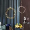 Two decorative LED wreaths hang in front of curtains, with a table holding decorative items in the foreground. Produktbild-Vorschau