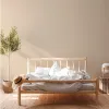 A bedroom scene with a bed, plant, and straw hat. Produktbild-Vorschau