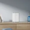 A white Reolink Home Hub Pro is placed on a wooden shelf next to a book and a blue vase. Podgląd zdjęcia produktu