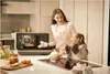 A mother and daughter are in a kitchen, looking at a microwave with food inside. Produktbild-Vorschau