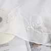 A close-up view of a white sheer curtain with embroidered floral and scroll details. Produktbild-Vorschau