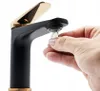 A hand is holding a coin near a black and gold faucet. Náhled obrázku produktu