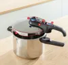 A pressure cooker is shown on a wooden table with a white countertop in the background. The pressure cooker has numbered labels pointing to different parts. Produktbild-Vorschau