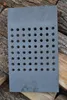 A gray cast iron grate with many holes is placed on top of stacked logs. Voir les images du produit