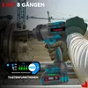 A person's gloved hands are holding a cordless impact wrench, which is attached to a large pipe fitting. Construction cranes are visible in the background. Podgląd zdjęcia produktu
