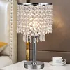 A crystal table lamp sits on a white surface next to a bed, with a cup of coffee in the foreground. Podgląd zdjęcia produktu