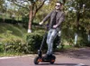 A man is riding an electric scooter on a paved path in a park-like setting. Náhled obrázku produktu