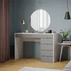 A modern vanity table with a round mirror, lamp, and drawers, set in a room with blue walls and wooden flooring. Anteprima dell’immagine prodotto