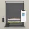 A smart home setup with an electric roller blind, a remote control, a smart speaker, and a smartphone displaying the blind's control app.