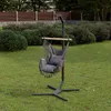 A hanging chair with cushions is set up on a green lawn in a backyard, with a fence and bushes in the background. Produktbild-Vorschau