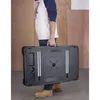 A person is carrying a folded black workbench. Náhľad obrázku produktu