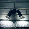 A close-up shot of a black and silver outdoor wall light fixture with two adjustable lamps, mounted on a textured gray brick wall. Produktbild-Vorschau
