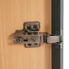 Close-up of a cabinet hinge attached to a wooden door and a dark frame. Náhľad obrázku produktu