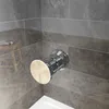 A close-up view of a shower valve handle in a bathroom with tiled walls. Produktbild-Vorschau