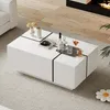 A modern white coffee table with black accents is placed on a light gray rug in a living room setting. The table has decorative items like vases, books, and drinks on it. Voir les images du produit