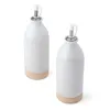 Two white ceramic oil and vinegar bottles with unglazed beige bases, shown from a diagonal angle against a white background. Náhled obrázku produktu