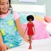A young girl is holding a Barbie doll in a bedroom setting with colorful pillows. Podgląd zdjęcia produktu