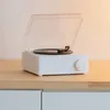 A white turntable-style Bluetooth speaker sits on a wooden surface. Podgląd zdjęcia produktu