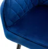 A close-up view of a dark blue velvet dining chair, showing the quilted backrest and seat. Náhled obrázku produktu