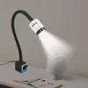 A machine lamp with a magnetic base is positioned on a desk next to an open book and a small white lamp. Podgląd zdjęcia produktu