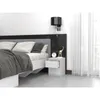 A bedside table next to a bed in a bedroom. Voir les images du produit