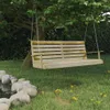 A wooden swing bench hanging from a tree in a garden setting. Voir les images du produit