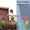 A woman on a balcony with hanging flower pots, and a display of colorful hanging flower pots. Produktbild-Vorschau