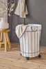 A laundry basket with a towel draped over it, next to a stool with a vase and dried flowers. Náhled obrázku produktu