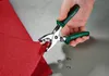 A hand is using a tool to attach a snap fastener to a piece of red fabric. Produktbild-Vorschau