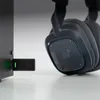 A close-up shot of a black wireless headset and its USB adapter plugged into a black device. Anteprima dell’immagine prodotto
