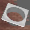 A silver-colored metal flange or rosette with a square outer edge and a circular opening in the center, set against a blurred background of reddish-brown bricks. Produktbild-Vorschau