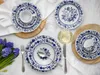 A table setting with blue and white patterned plates, cups, and cutlery, along with a bunch of blue hyacinths. Náhľad obrázku produktu