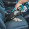 A person is using a cordless vacuum cleaner to clean a car seat. Podgląd zdjęcia produktu