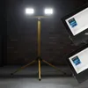 A tripod work light with two LED panels is shown in a dimly lit brick-walled room. Náhled obrázku produktu
