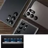 Multiple smartphone camera lens protectors are shown on a wooden surface, with a close-up of the bottom edge of a smartphone with three lens protectors attached. Produktbild-Vorschau