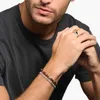 A man's hands wearing jewelry, including a ring and bracelets. Náhľad obrázku produktu