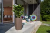 A modern patio with a large planter and a palm tree, along with colorful inflatable rings and a small table. Náhľad obrázku produktu