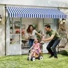 A family enjoys a sunny day in their backyard, with the awning providing shade over a patio door. Náhled obrázku produktu