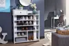 A white shoe rack filled with shoes against a blue wall. A desk and chair are visible in the background. Produktbild-Vorschau