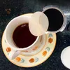 A cup of coffee with coffee grounds and a filter paper. Produktbild-Vorschau