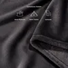 A close-up of a dark gray plush blanket with icons and text indicating its use for picnics, camping, and at home. Produktbild-Vorschau