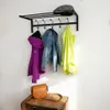 A coat rack with several items of clothing and a hat hanging on it, with a bag on a wooden crate below. Produktbild-Vorschau