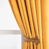A close-up of a yellow velvet curtain held back by a decorative bronze leaf-shaped tie-back. Produktbild-Vorschau