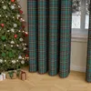 A Christmas tree decorated with ornaments and lights stands next to plaid curtains in a room with gifts on the floor. Podgląd zdjęcia produktu